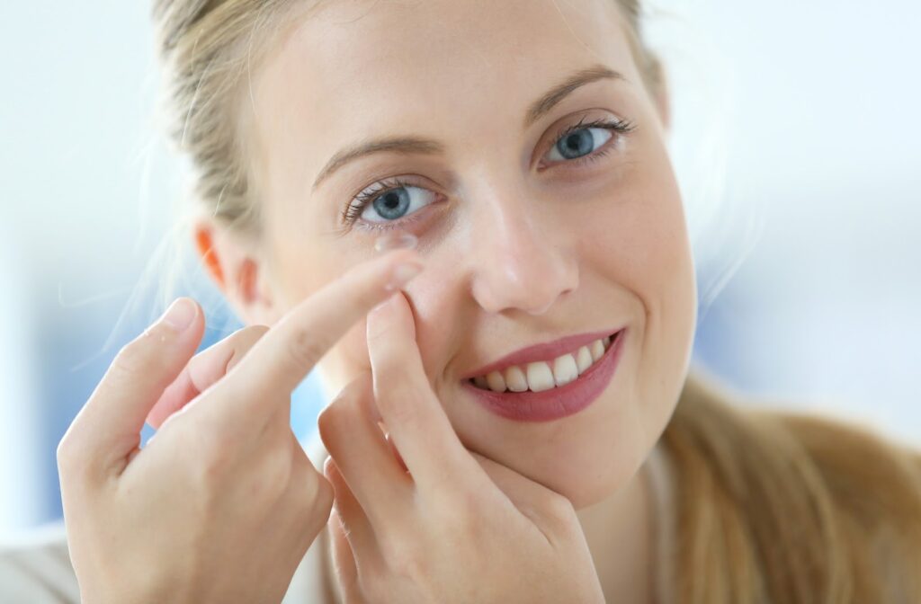 Young happy woman putting on contact lenses